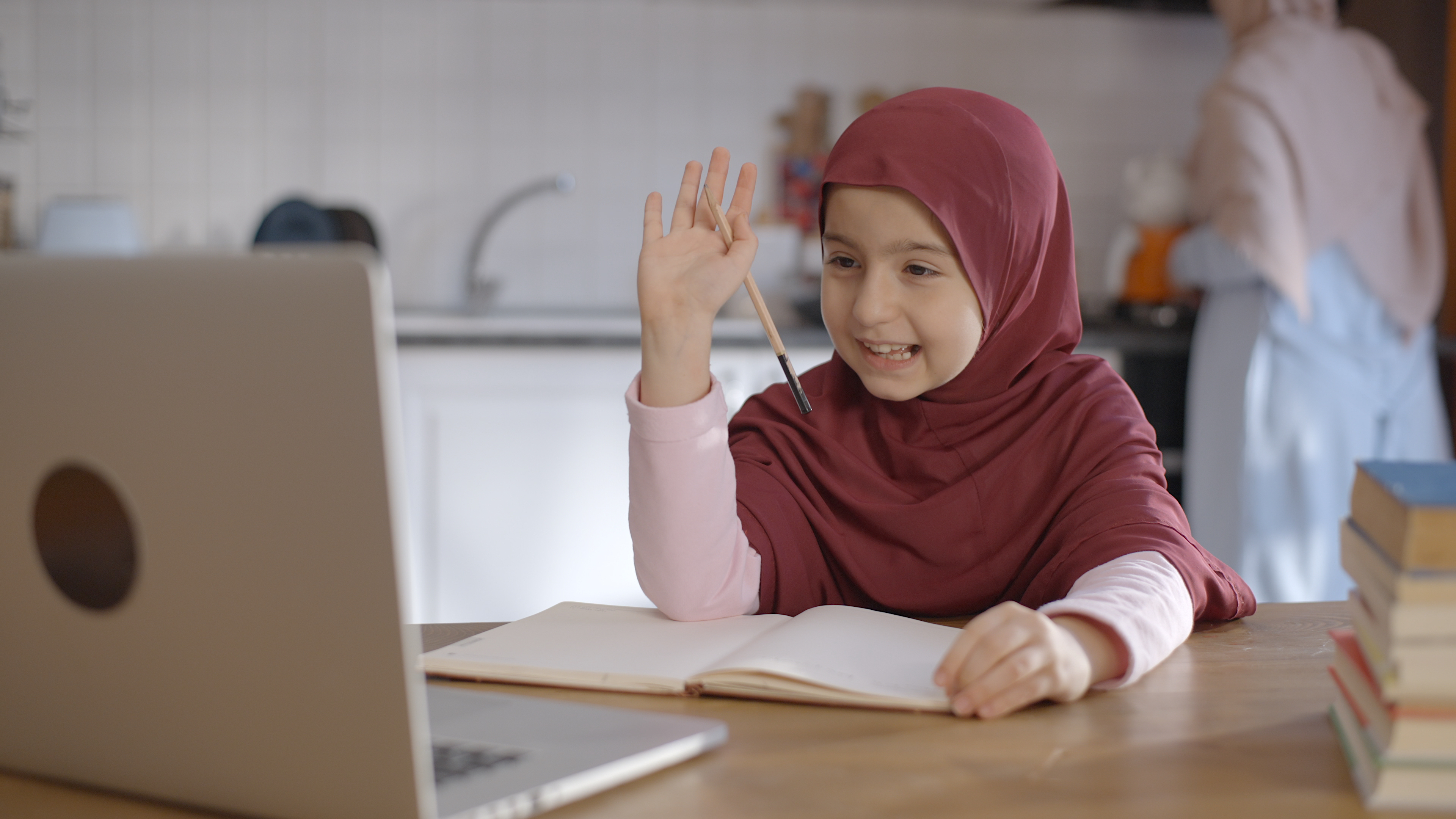 A student smiling to the cam and raising her hand up